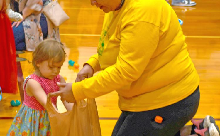 Taking part in the 18th annual Easter Eggs-travaganza April 19 at the Webster Armory was Aria Fellbaum. Meanwhile mom Jacquie Fellbaum helps hold a plastic bag for her to store her loot. The event is annually sponsored by First Baptist Church, Webster. Reporter &amp; Farmer | Jessica Washenberger