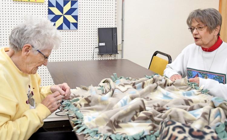 Webster residents Margaret McKittrick and Jan Ingalls visit while working on a tie blanket during the Day County Arts Center’s Dec. 1 Christmas tree lighting event. The blankets were made for a charity organization. Reporter &amp; Farmer | Amanda Dulitz