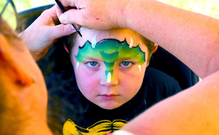 Dempsey Heupel, four, looks to embody the fierce dragon being painted on his face Aug. 9 during the Day County Fair. Kari Nelson, Webster, was the masterful artist behind many colorful children’s faces running around the Day County Fairgrounds. Heupel of Webster is the son of Jacob and Jessica Heupel. Reporter &amp; Farmer | Amanda Dulitz