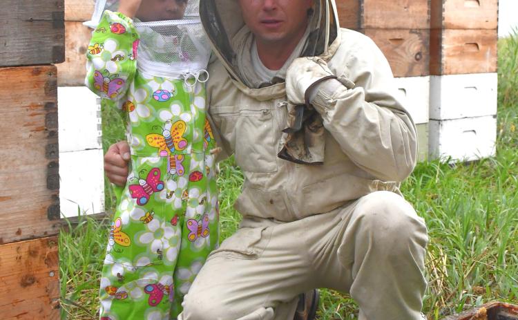 Will Marchuk and his three-year-old son Mark pose for a picture in one of Marchuk’s bee yards near Andover July 22. Marchuk is a commercial beekeeper who immigrated to the U.S. from Ukraine in 2009 and now operates over 4,200 hives. Reporter &amp; Farmer | Leyton Beardslee