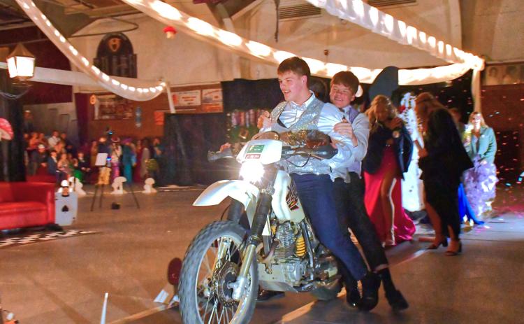 (Above) From left, Jack Snell and TJ Sonstebo start off the comedy side of the Grand March by driving through the armory on a motor-bike. Webster Area’s Grand March was turning into a confetti-water- bubble mess with students laughing as they entertained the crowd. Reporter &amp; Farmer | Connor Handrahan