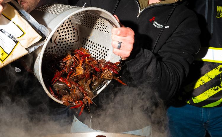 At left, Riley Reetz dumps a bucket of crawfish into a boiling pot of water during the crawfish boil fundraiser in Webster April 3. Proceeds from the event will go towards new playground equipment for Haase Baseball Field, according to organizers. This was the 11th year for the annual event, traditionally held on Good Friday. This was the first year the event was hosted by the Crawfish Committee. Reporter &amp; Farmer photo by Leyton Beardslee